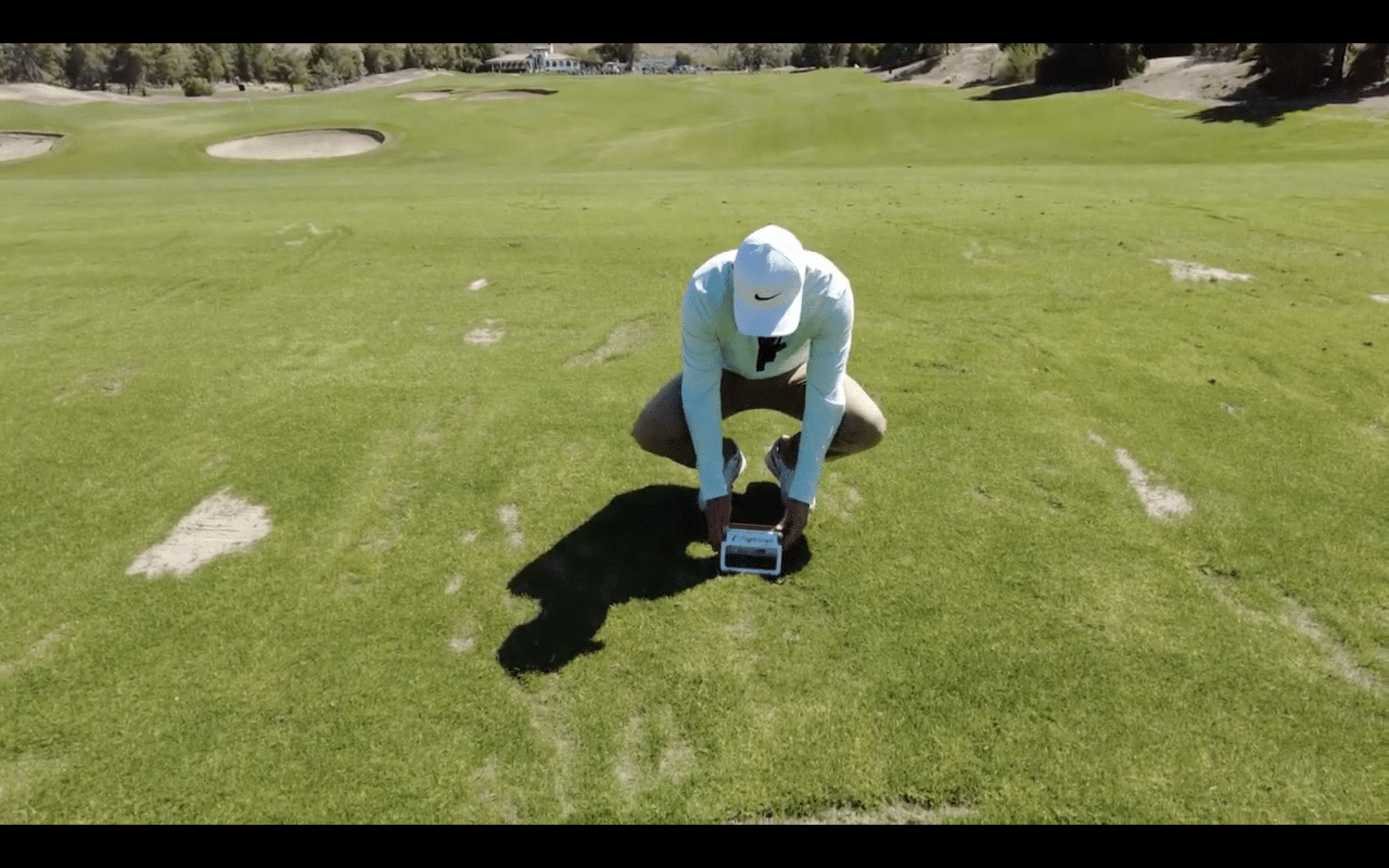 Person measuring grass on golf course fairway