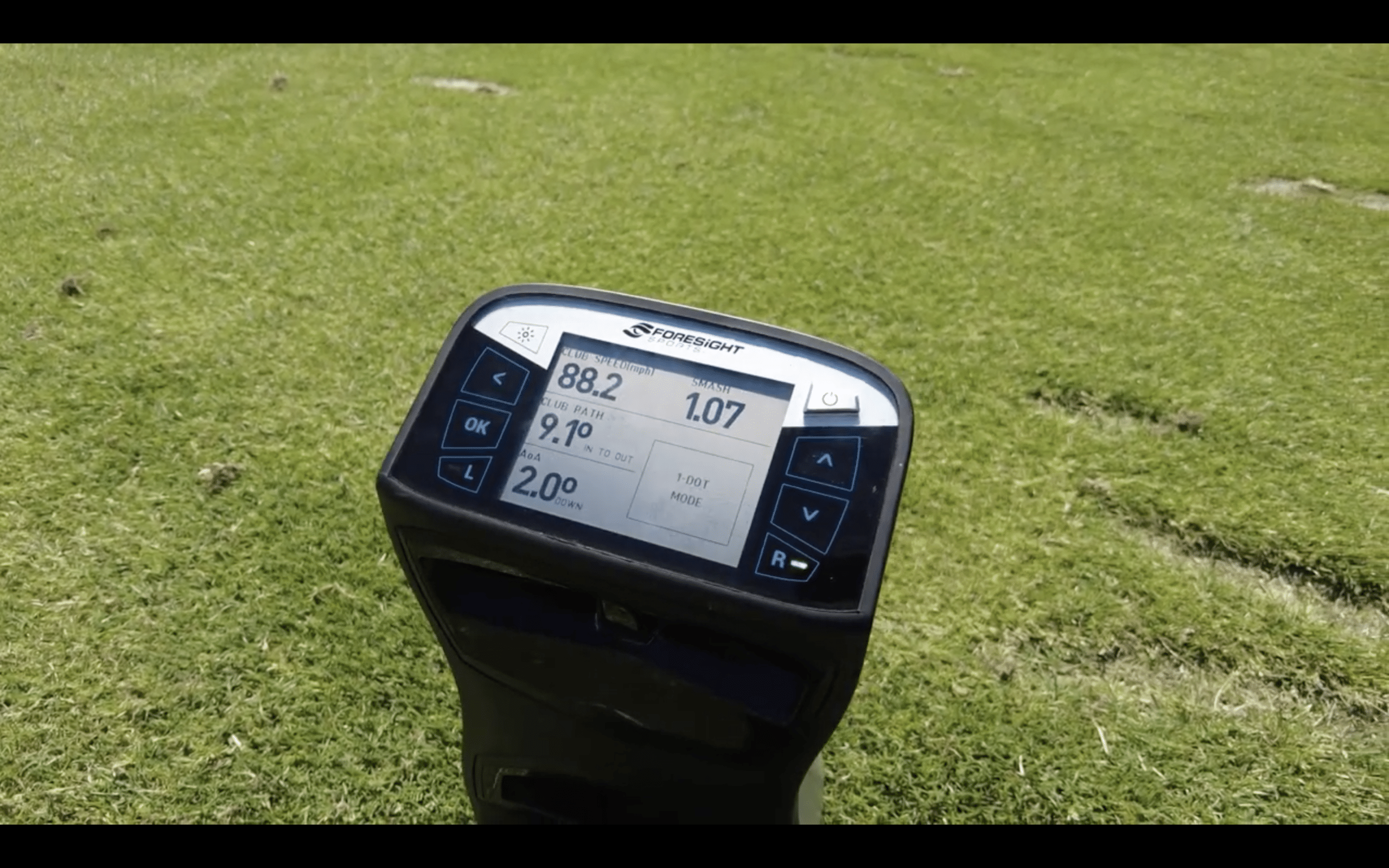 Golf launch monitor displaying swing data on grass