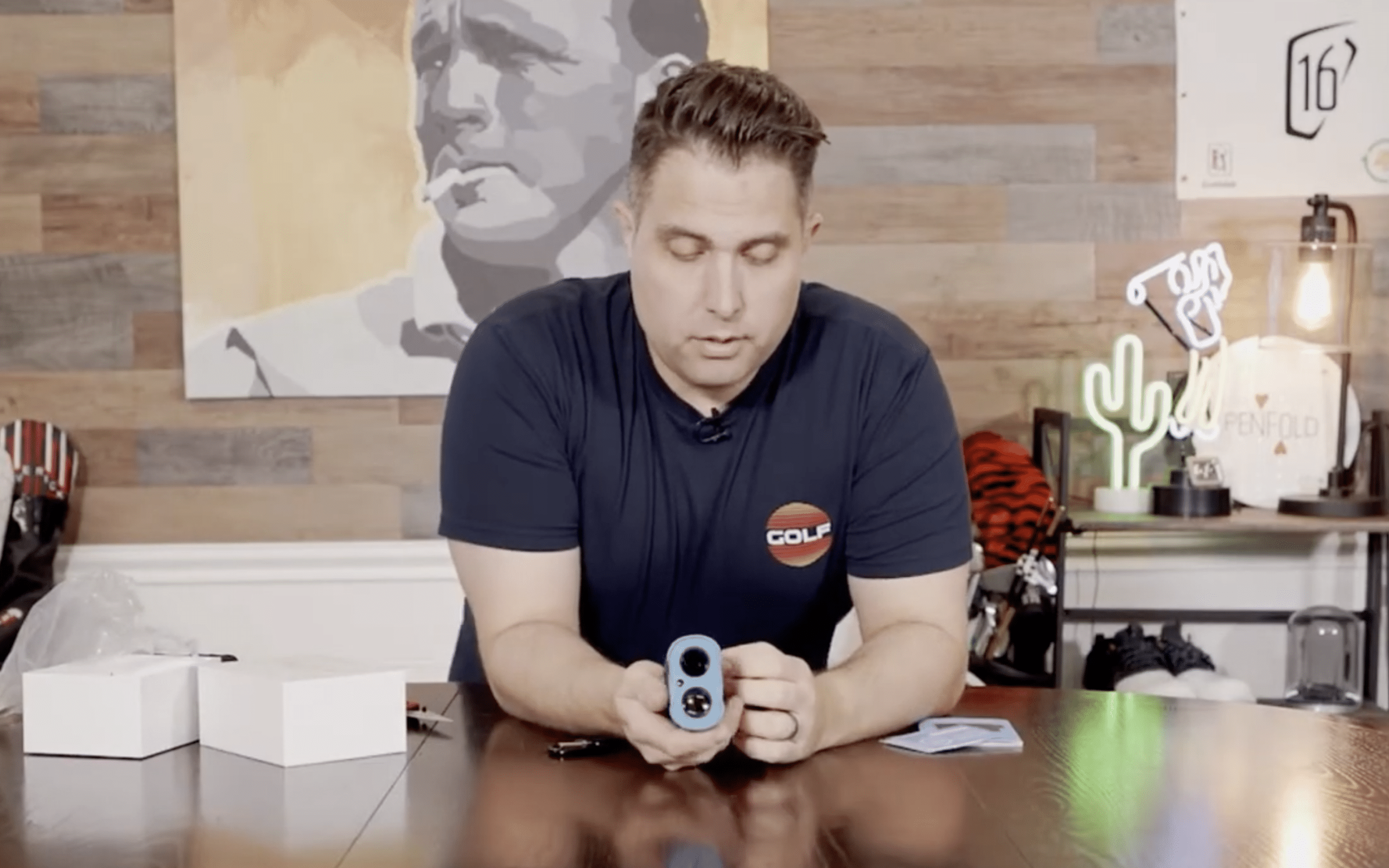 Man demonstrates blue golf rangefinder indoors