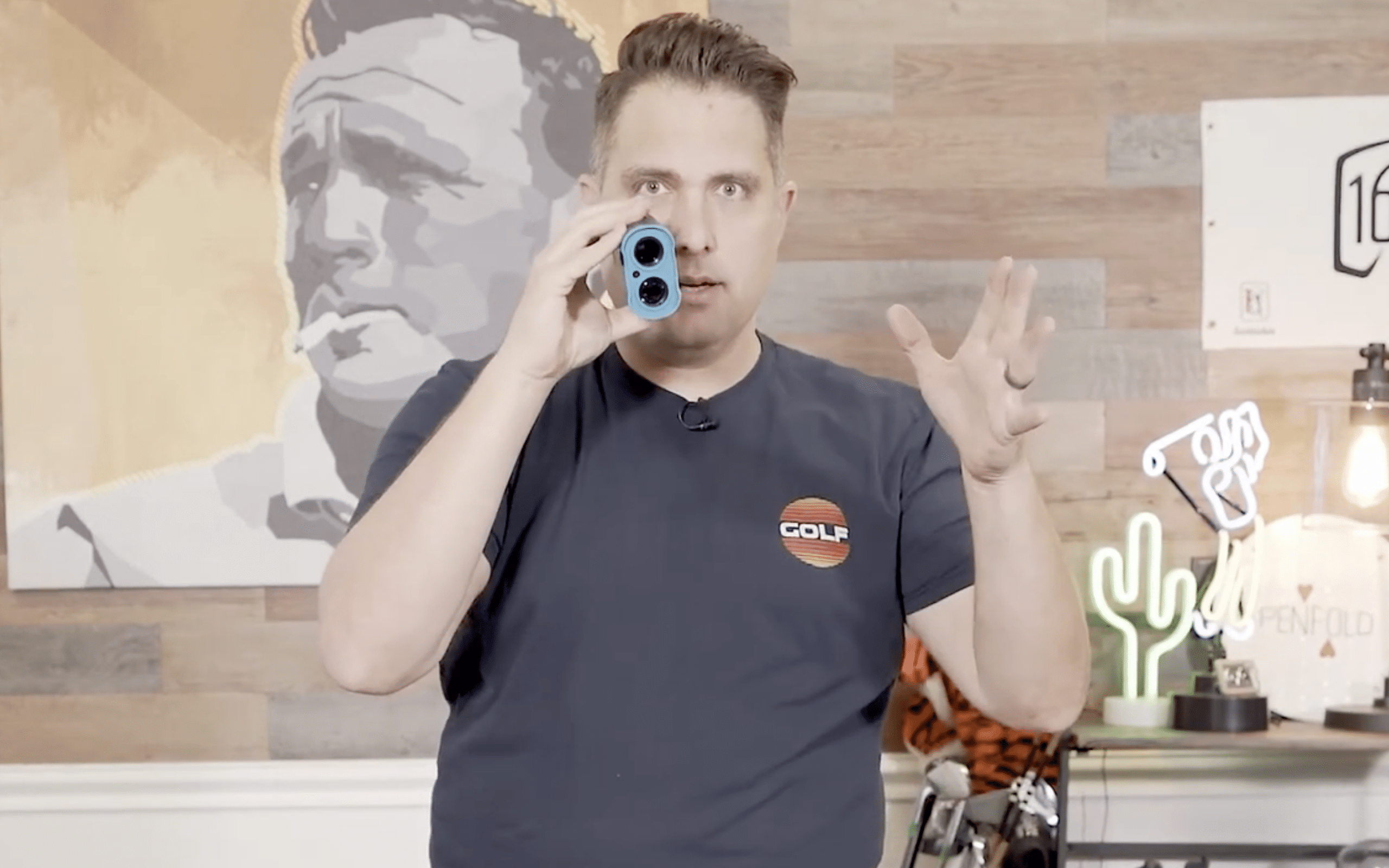 Man demonstrating blue golf rangefinder indoors