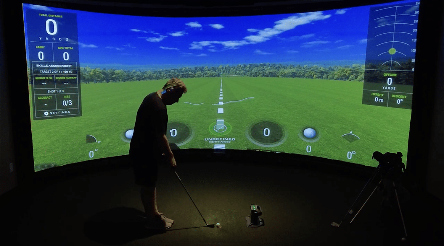 Golfer practicing swing in indoor simulator.