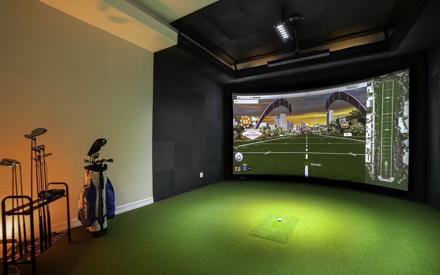 Indoor golf simulator with clubs and screen display