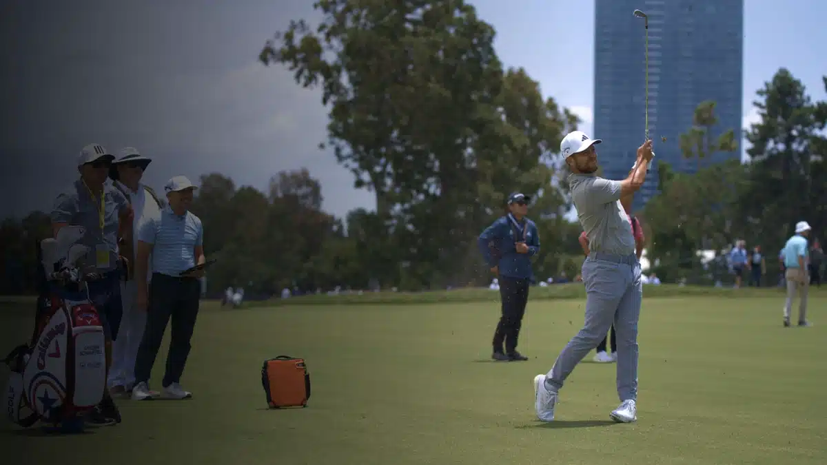 Golfer swinging club on green during tournament