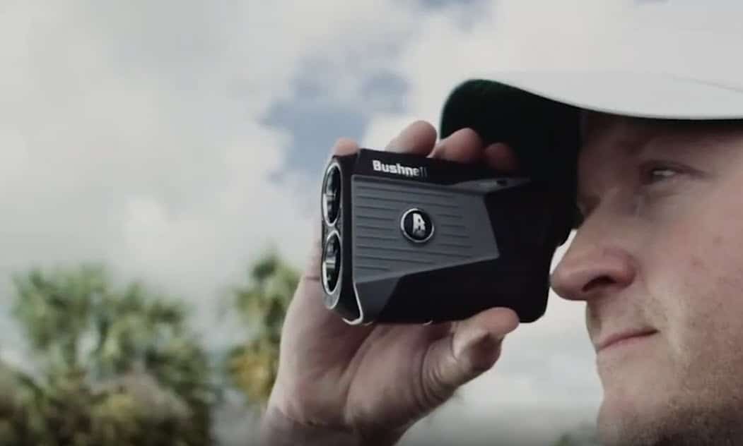 Man using Bushnell golf rangefinder outdoors