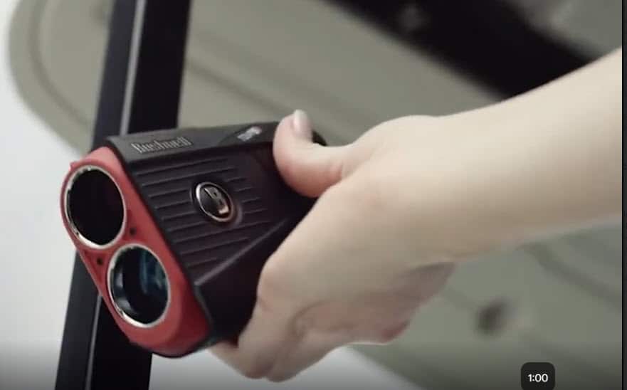 Hand holding a black and red rangefinder