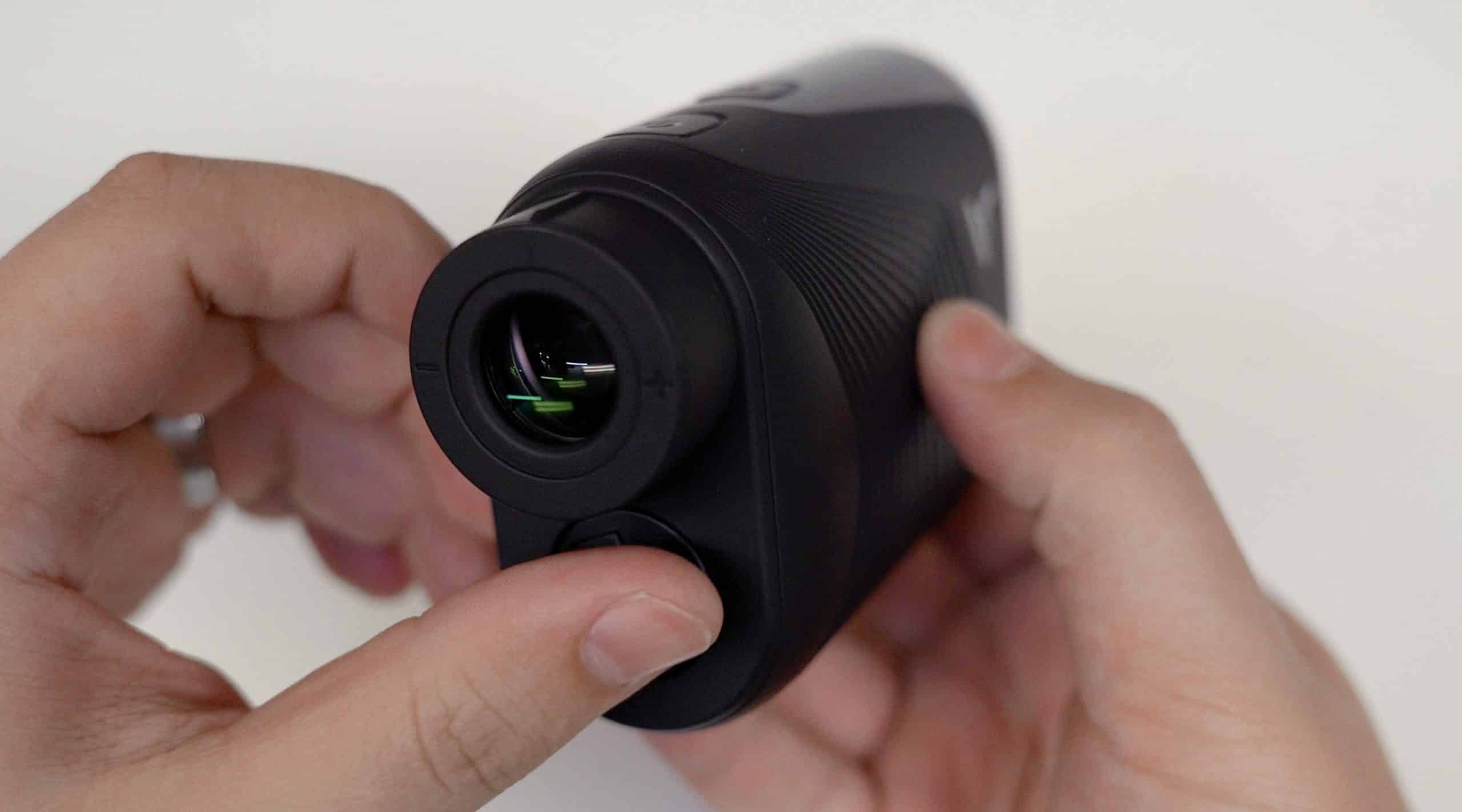 Person holding a black digital rangefinder
