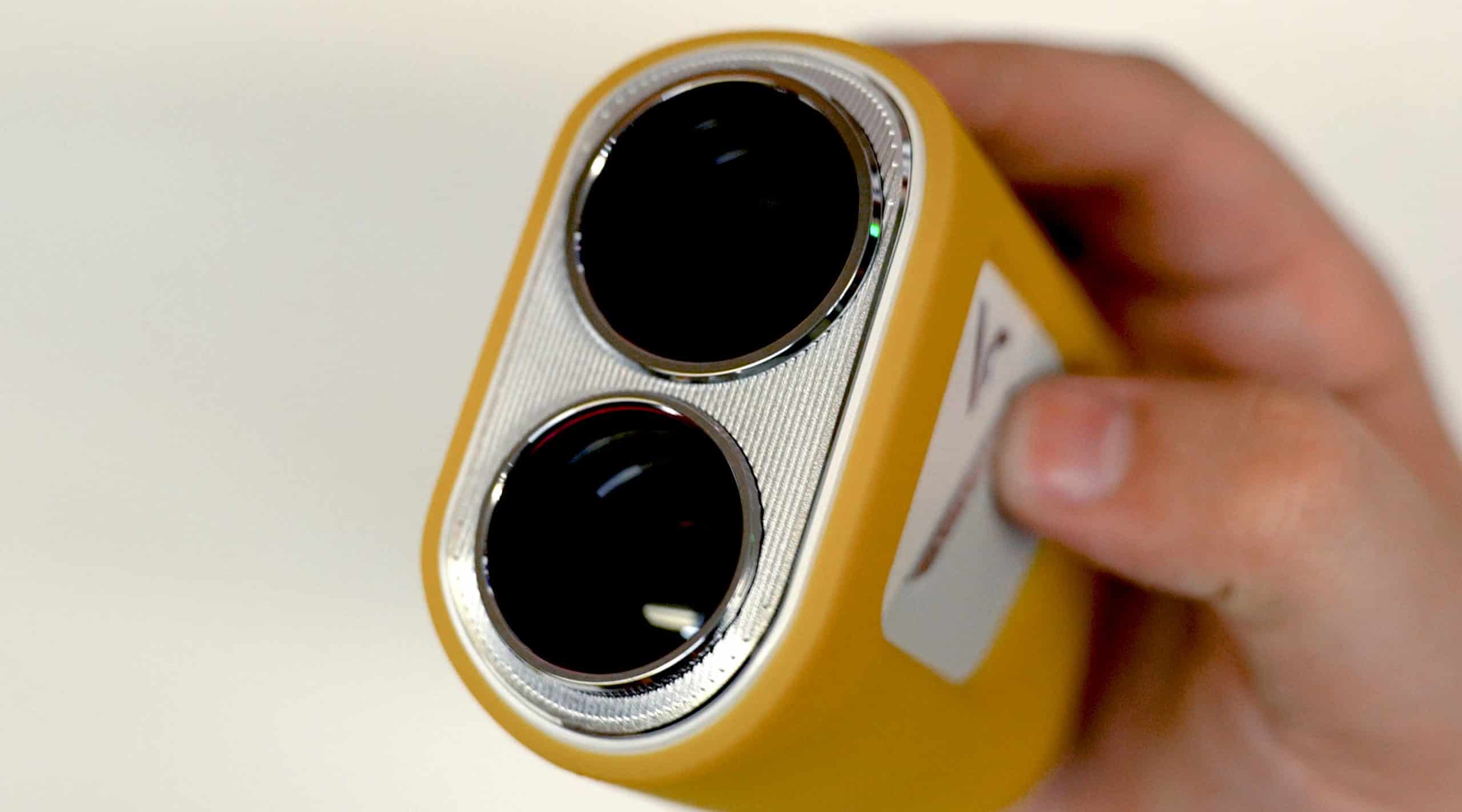 Hand holding yellow dual-lens camera device