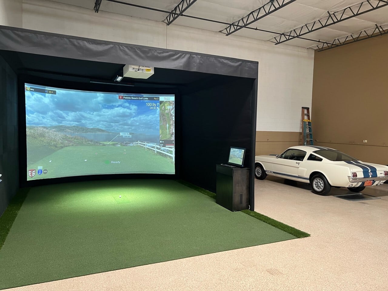 Indoor golf simulator next to classic white car