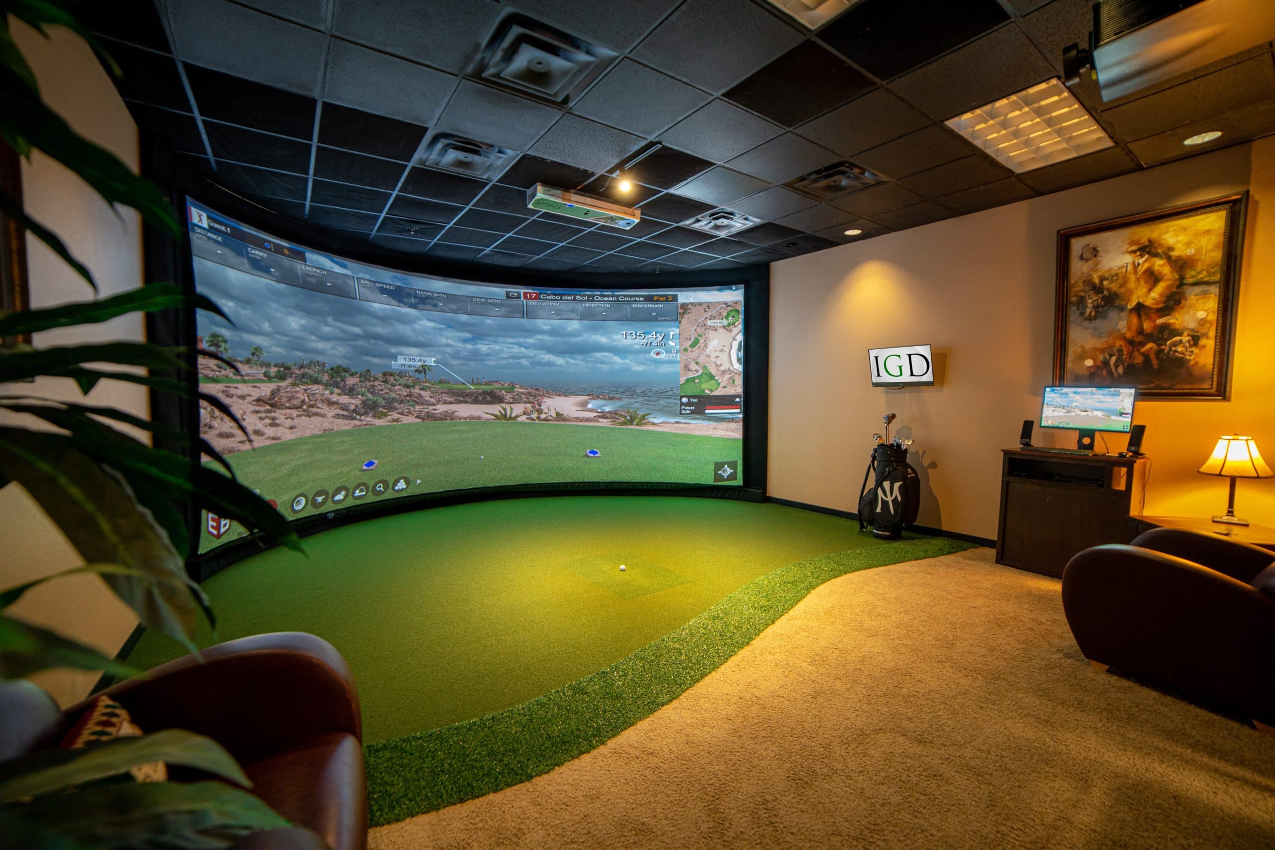 Indoor golf simulator room with screen and seating