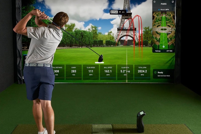 Golfer practicing with indoor golf simulator screen