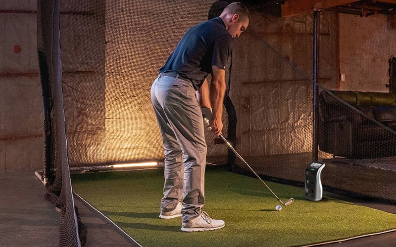 Golfer practicing swing indoors on artificial turf