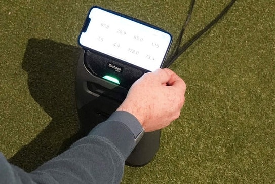 Person using golf launch monitor with smartphone display