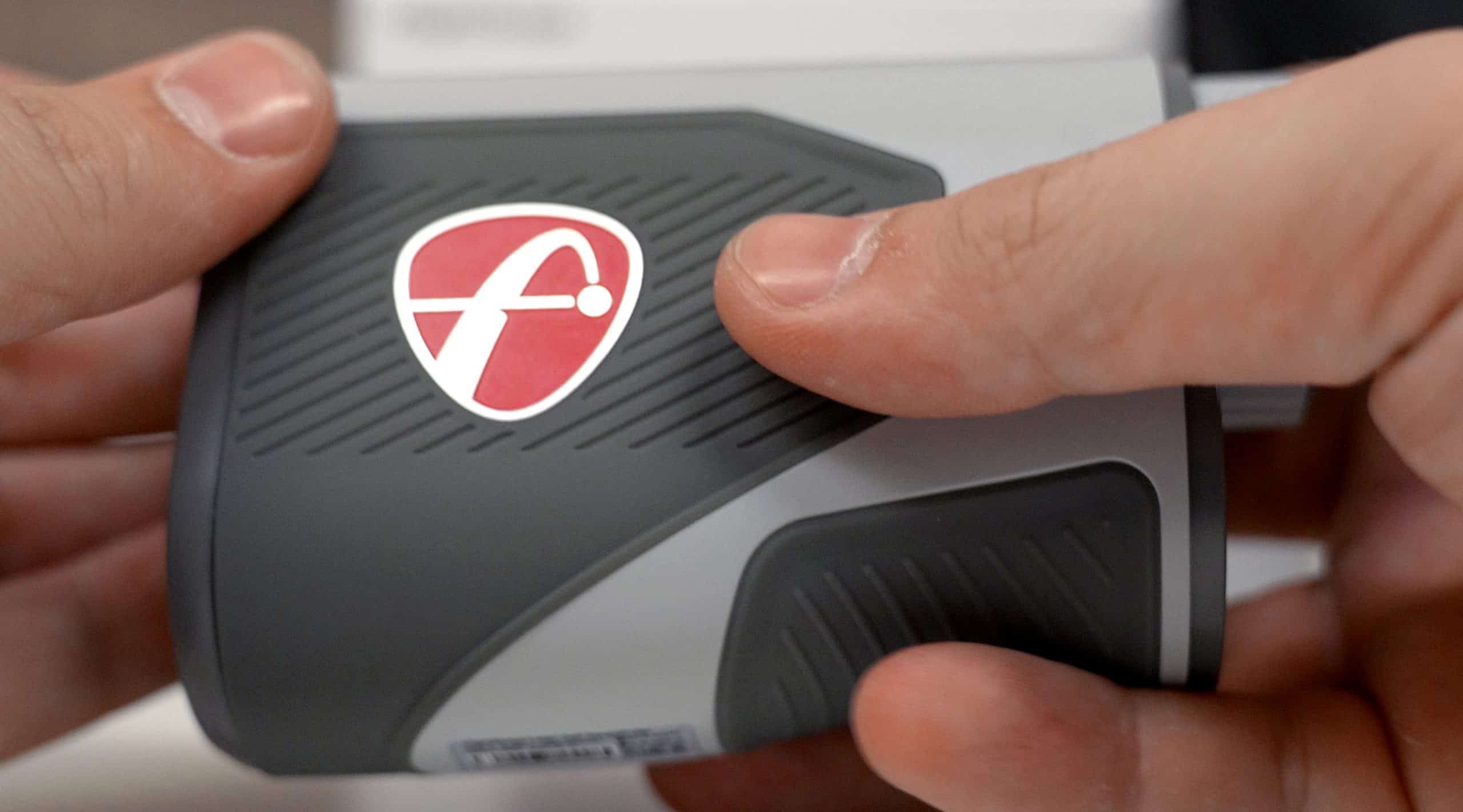 Hand holding gray device with red logo