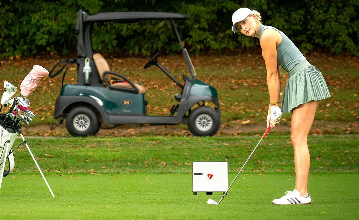 Golfer preparing to swing near golf cart