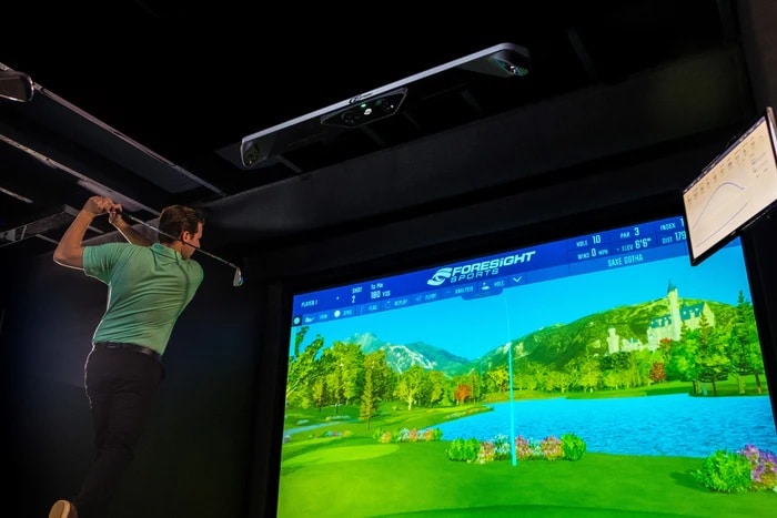 Golfer playing indoors on virtual golf simulator