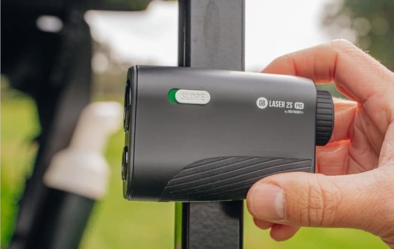 Hand holding black golf rangefinder with slope switch