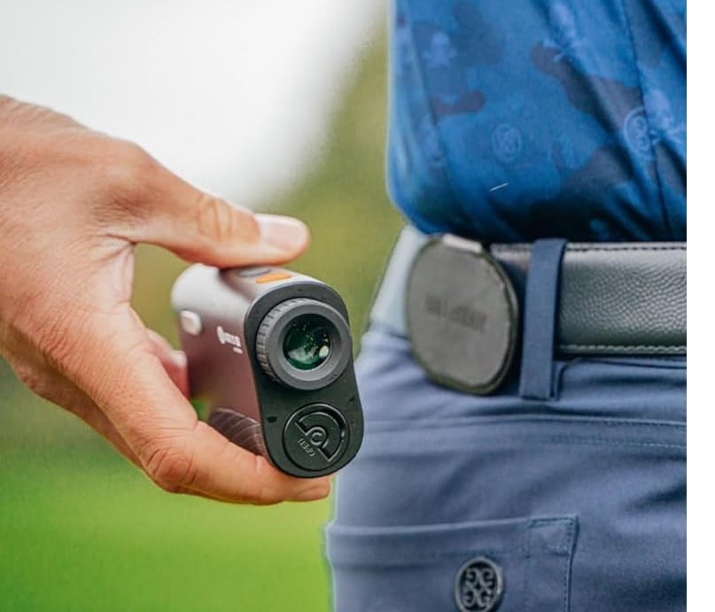 Golfer holding a laser rangefinder on course