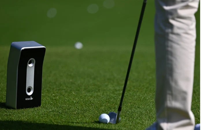 Golfer using launch monitor on green grass