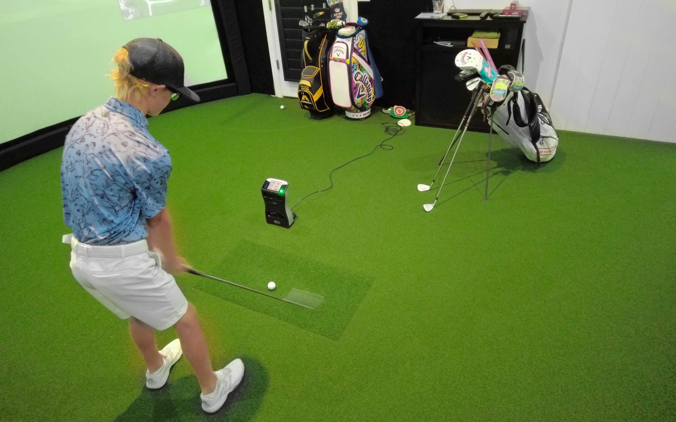 Person practicing golf indoors with simulator setup