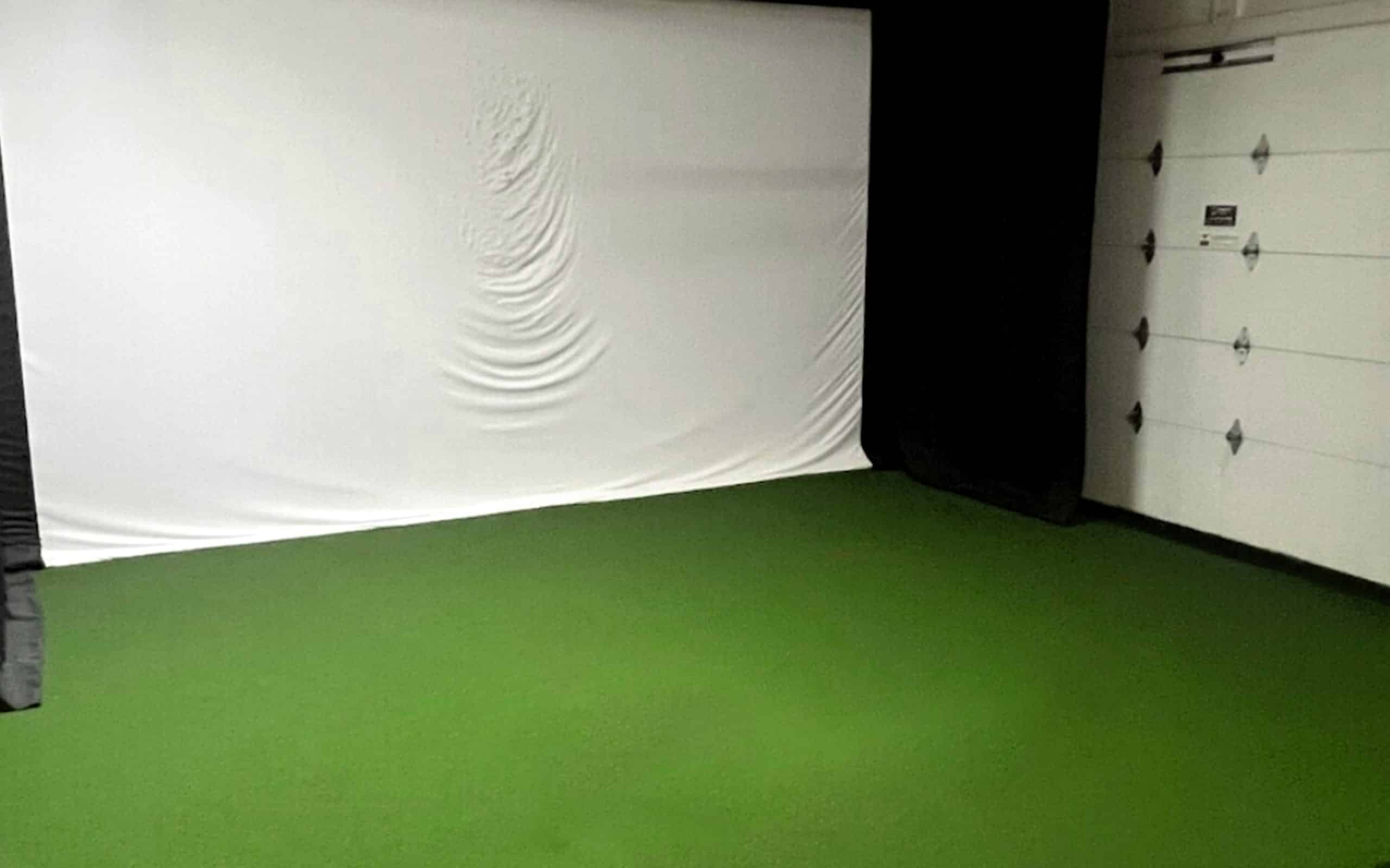 Indoor golf simulator setup with green turf