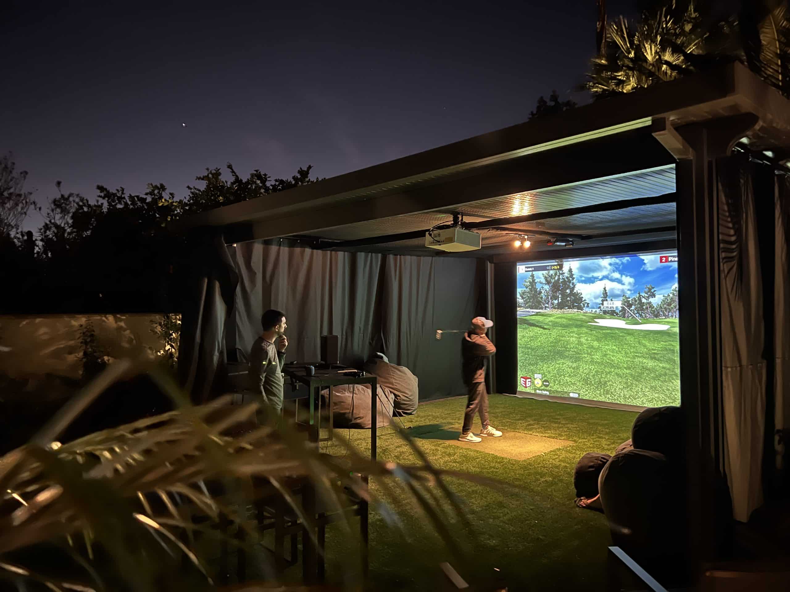 People playing golf simulator at night outdoors