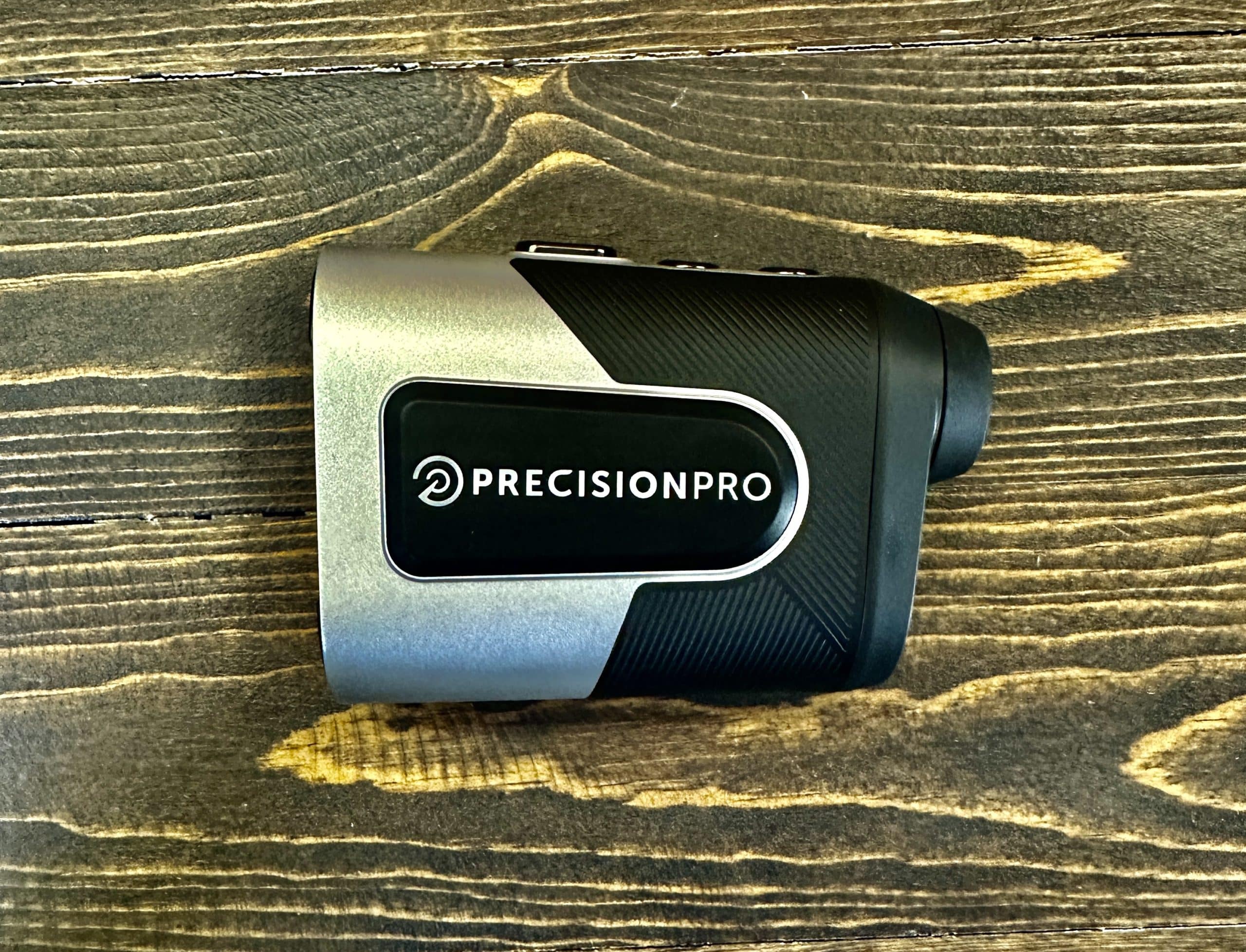 Precision Pro golf rangefinder on wooden surface