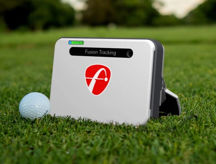 Golf launch monitor on grass beside ball