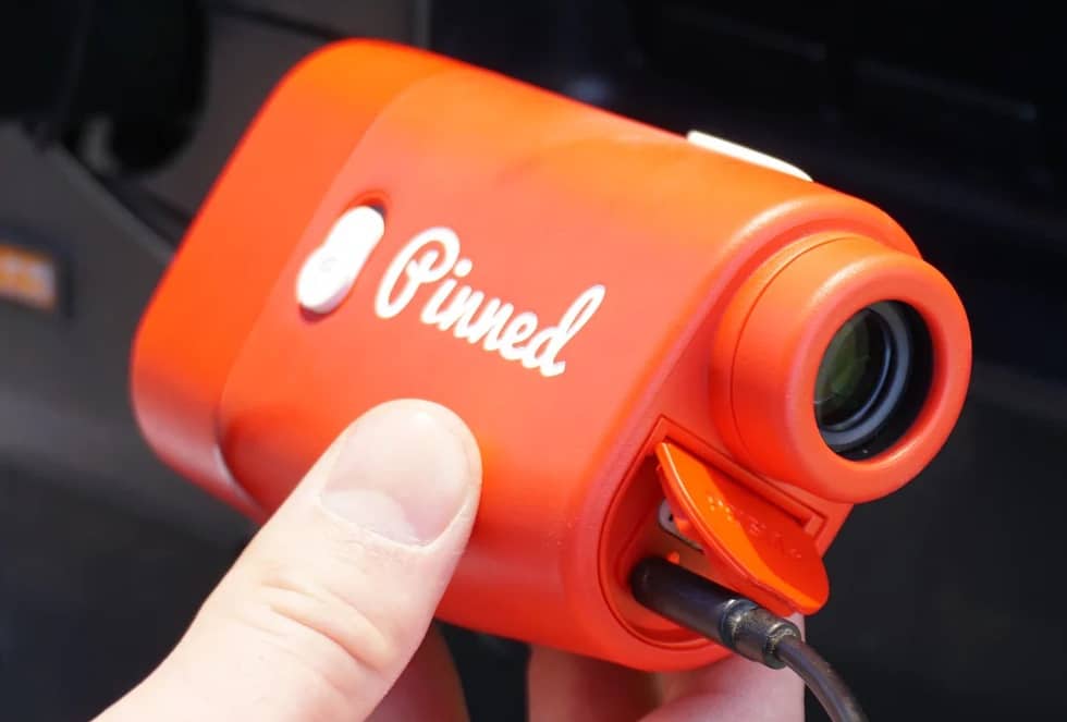 Hand holding red Pinned golf rangefinder device