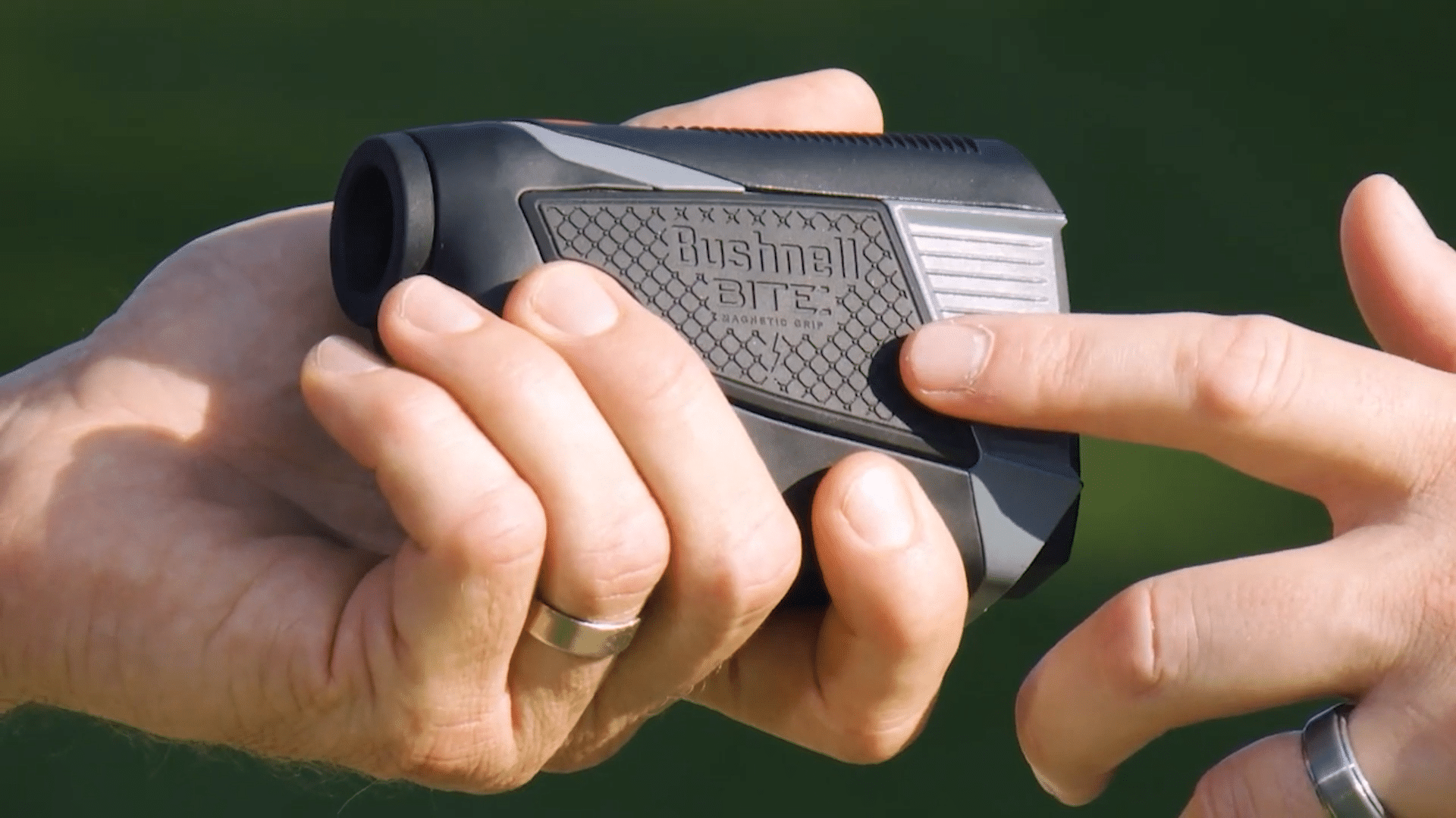Person holding a Bushnell golf rangefinder outdoors