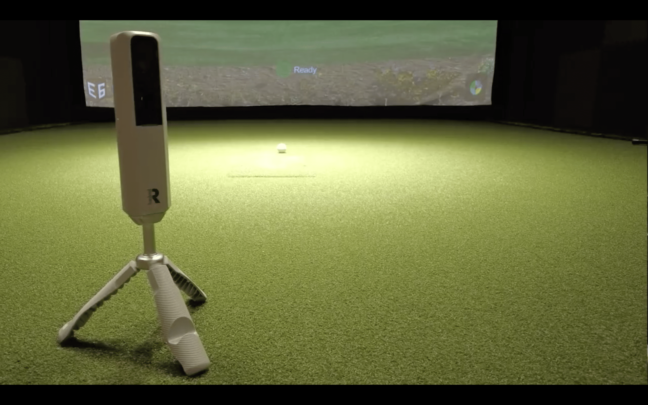 Golf simulator setup with launch monitor and screen