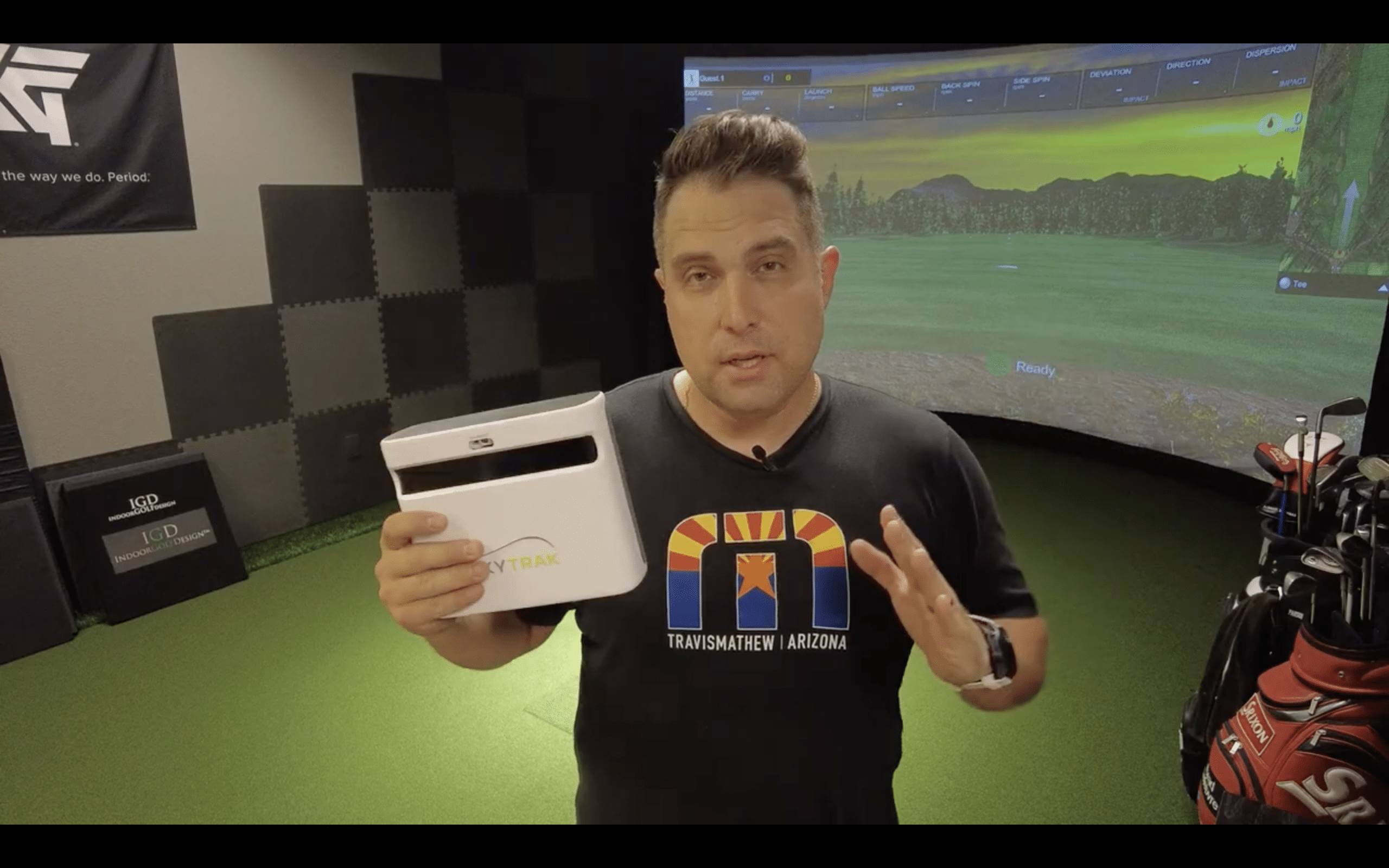 Man demonstrating SkyTrak golf launch monitor indoors
