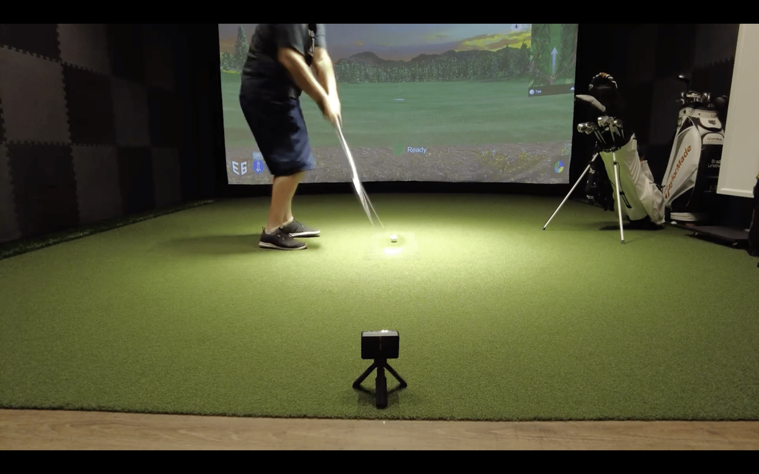Person swinging golf club in indoor simulator