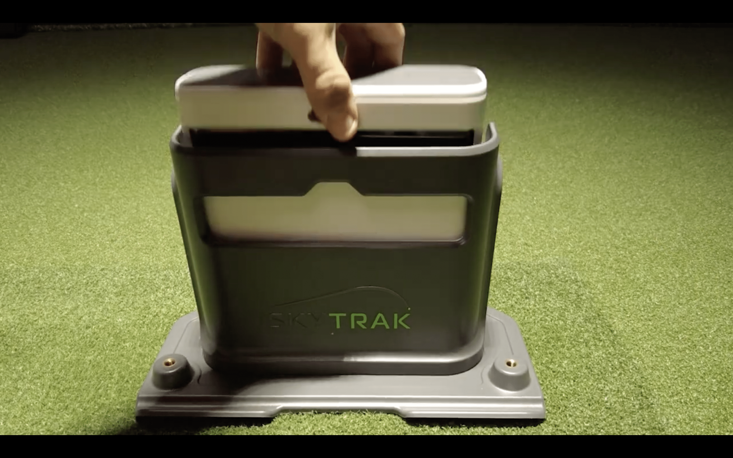 Person placing SkyTrak golf launch monitor in holder