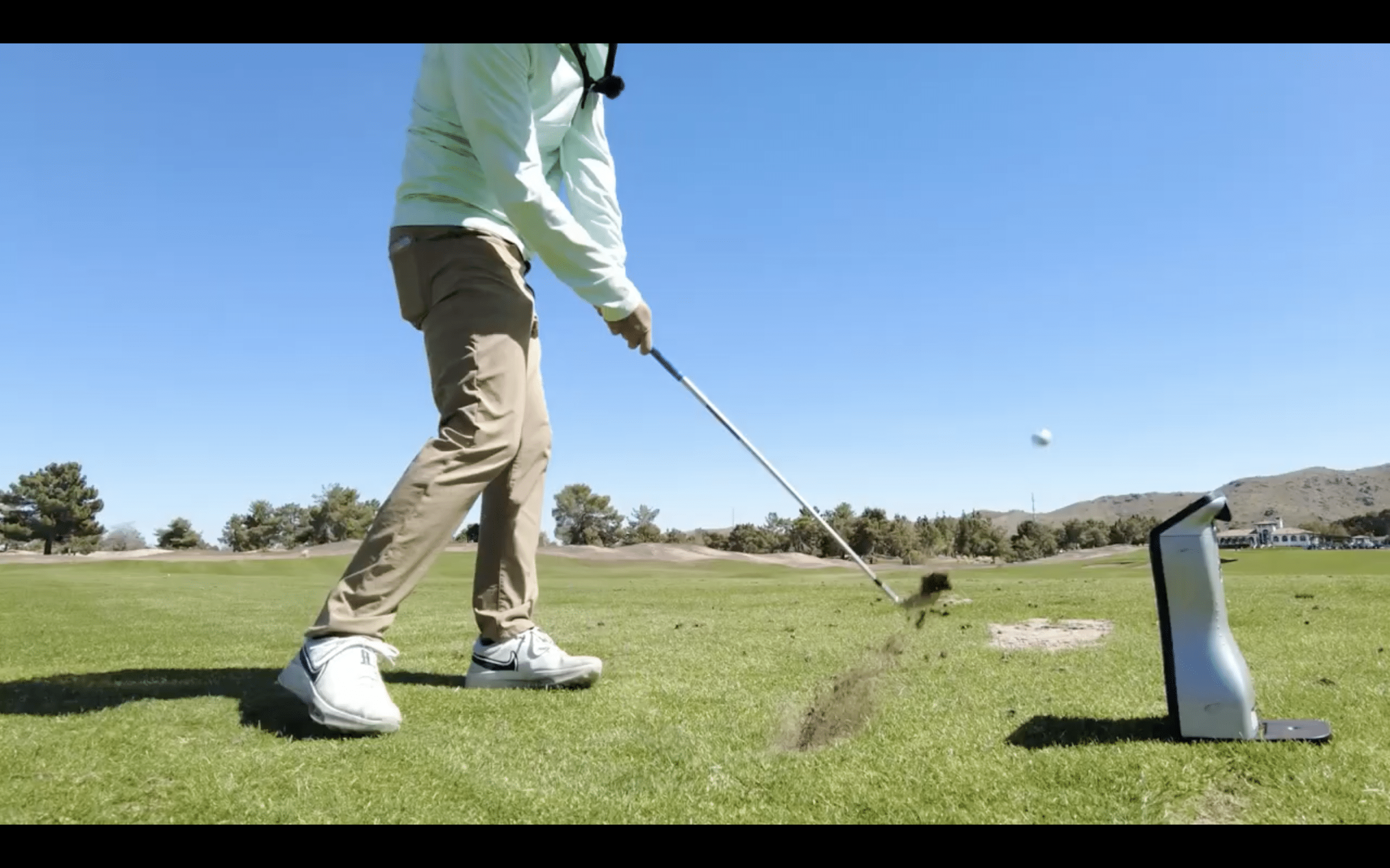 Golfer hitting ball on sunny course