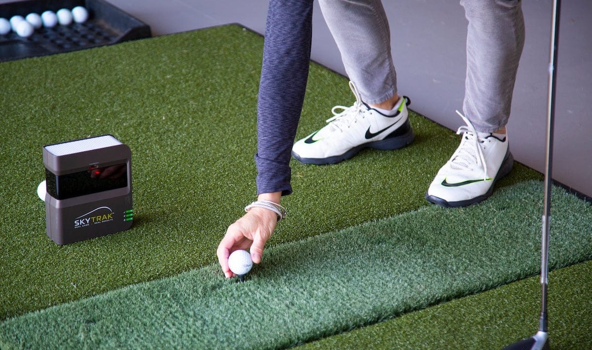 Golfer setting ball near SkyTrak launch monitor