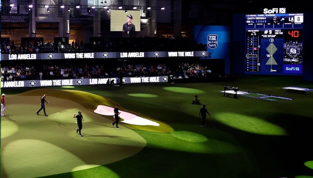Indoor golf tournament with scoreboard and audience