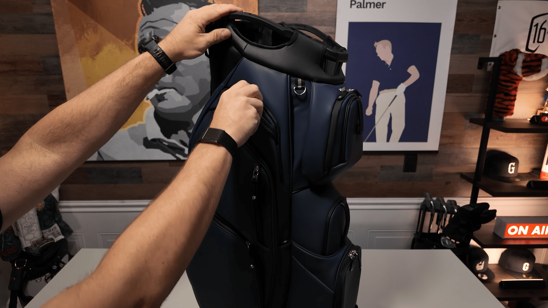 Person examining a navy golf bag indoors