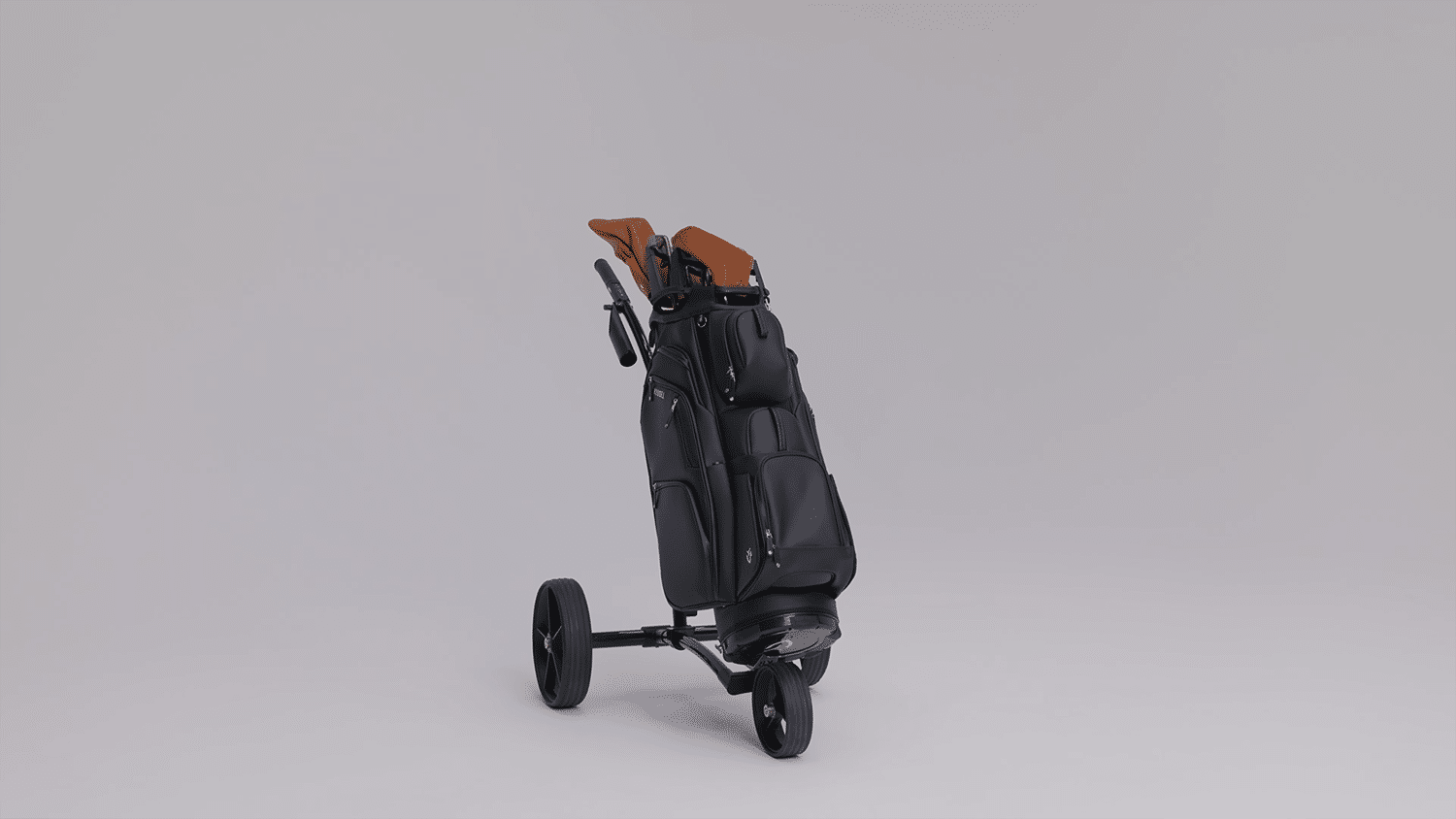 Black golf bag on three-wheel push cart