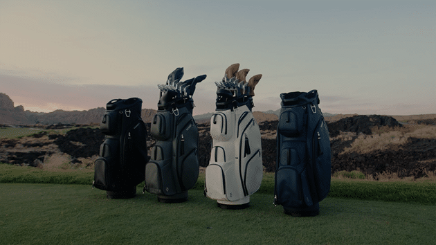 Four golf bags lined up on grassy course