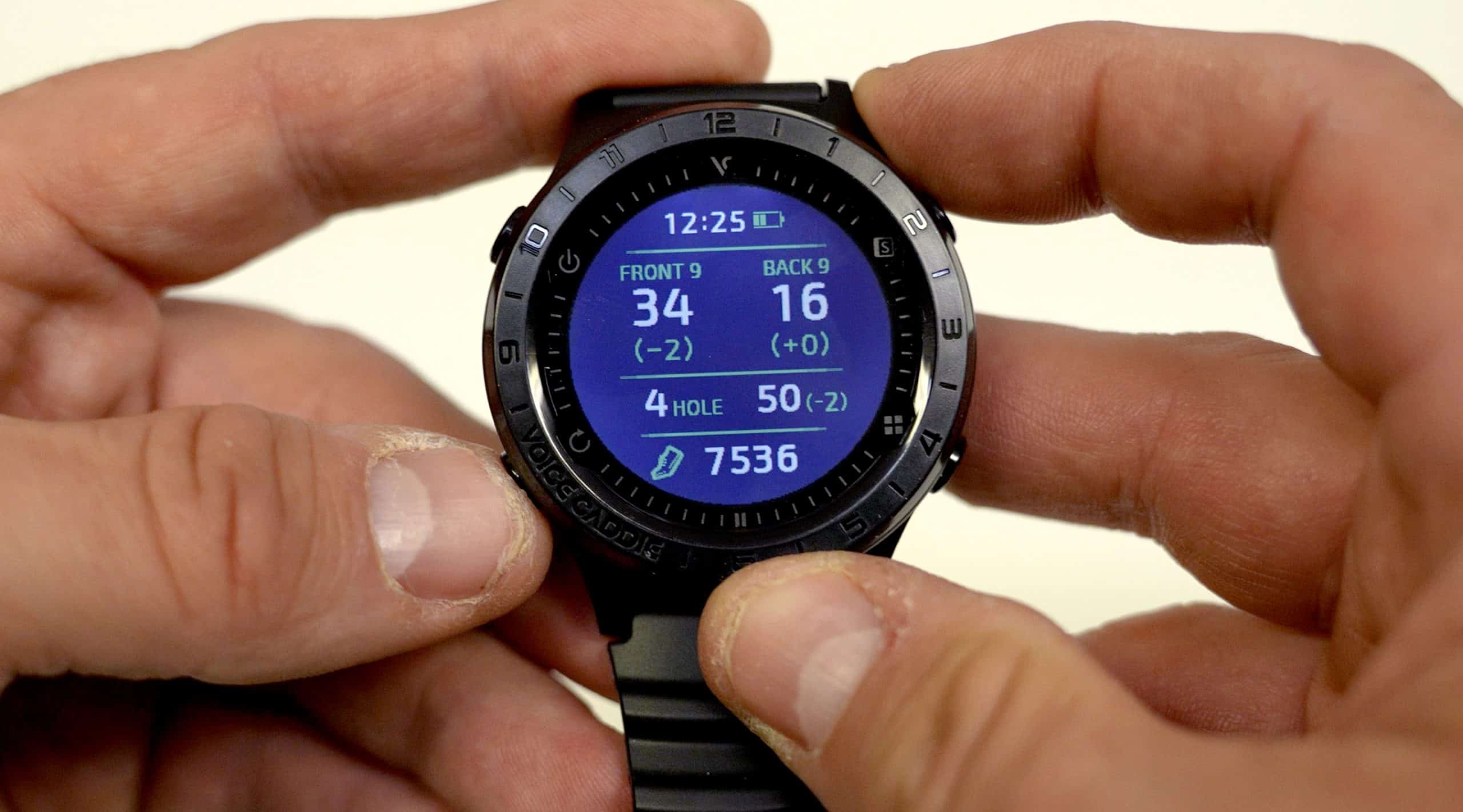 Person holding smartwatch displaying golf score data