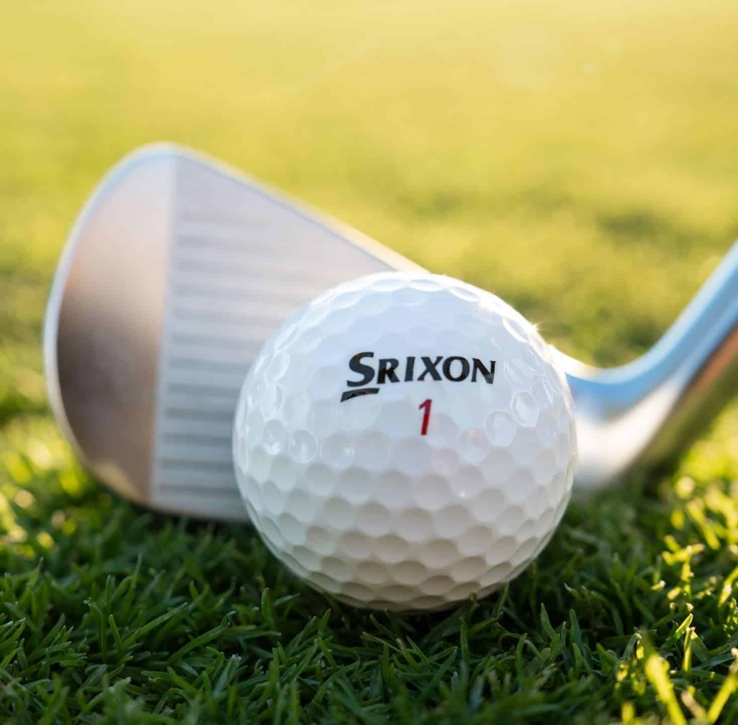 Golf ball and club on grass