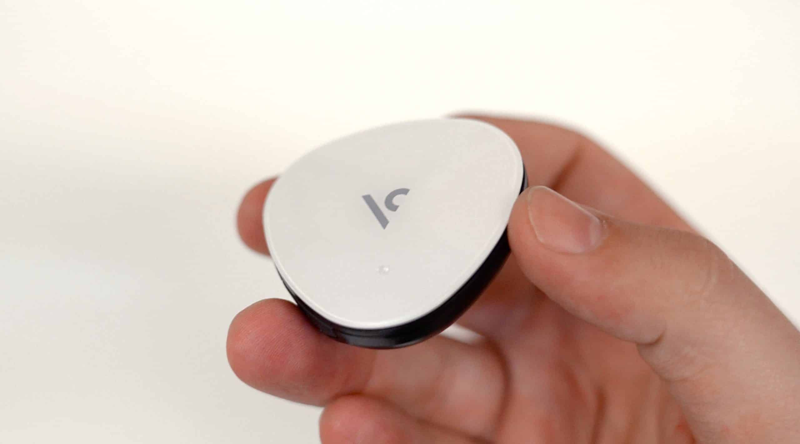 Hand holding a small white smart tracker