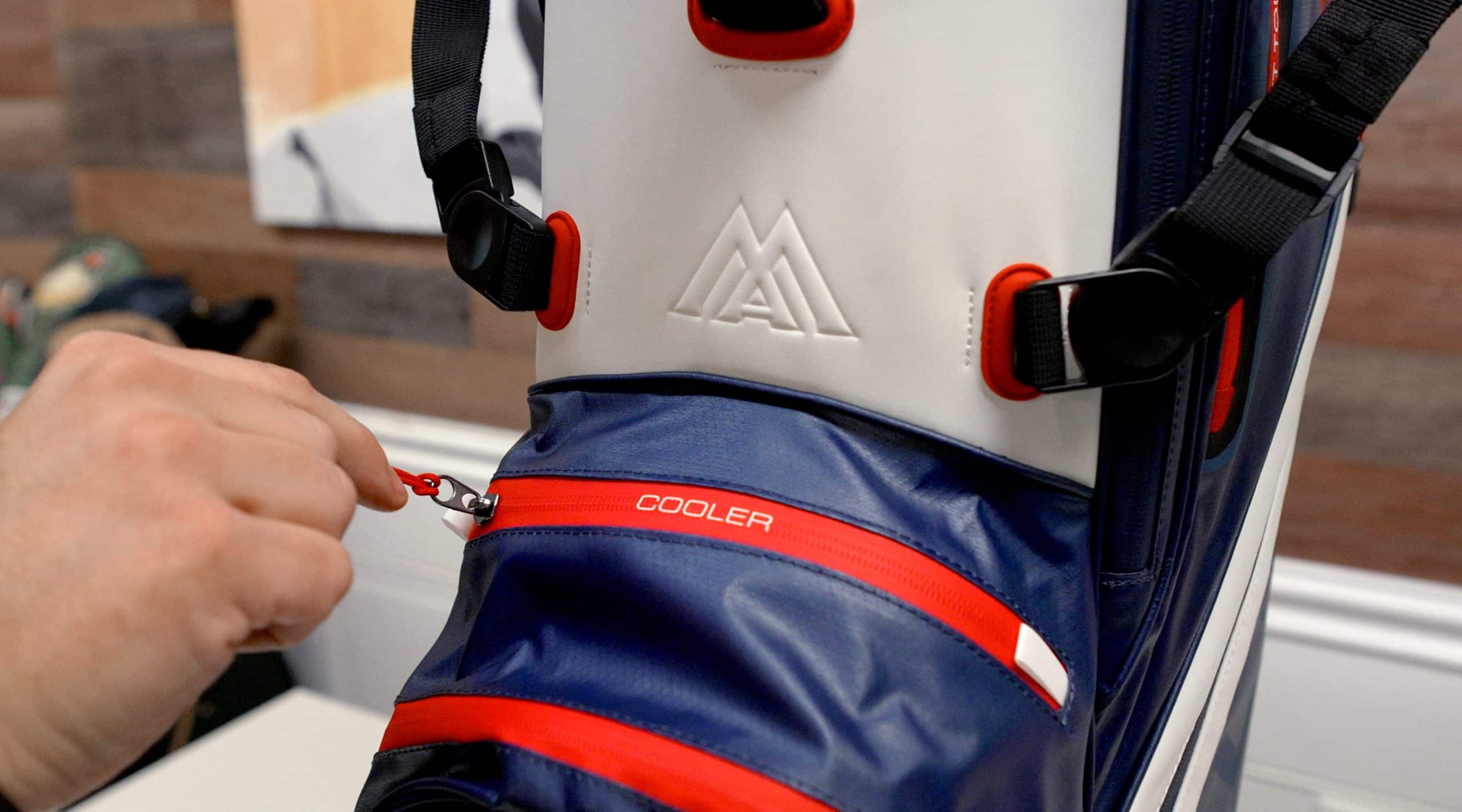 Person unzipping pocket on golf bag cooler compartment