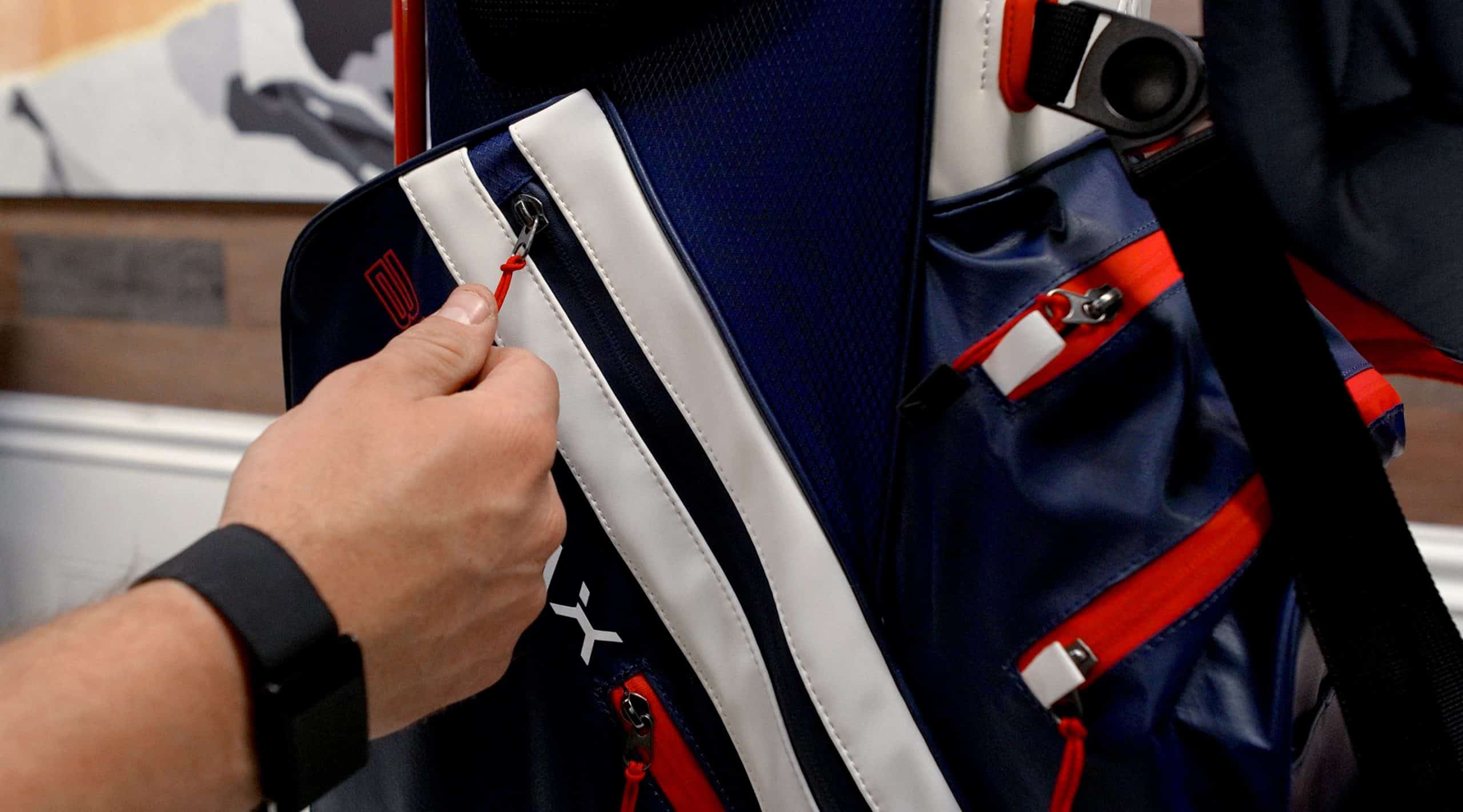 Person unzipping a navy blue sports bag