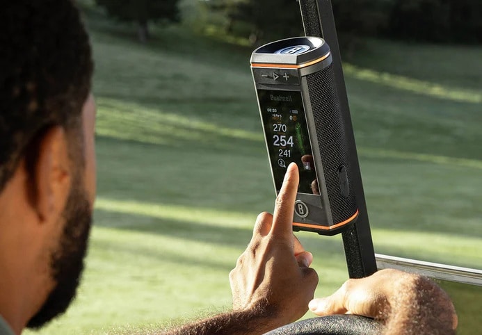 Golfer using touchscreen GPS device on golf cart