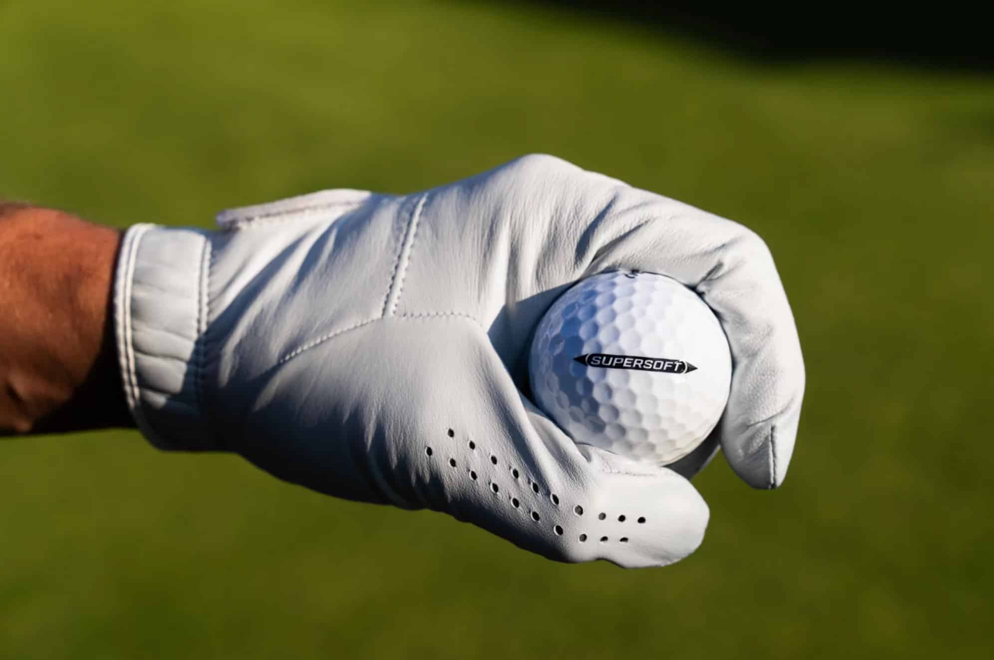 Gloved hand holding a Supersoft golf ball