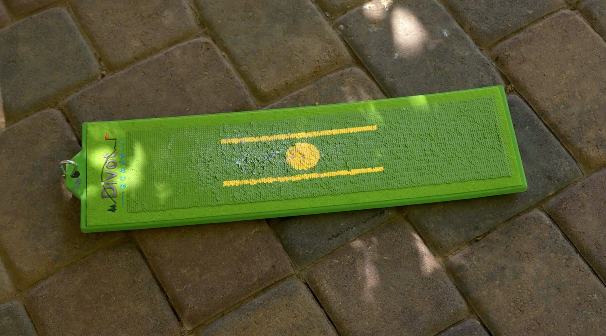 Green golf divot board on stone pavement