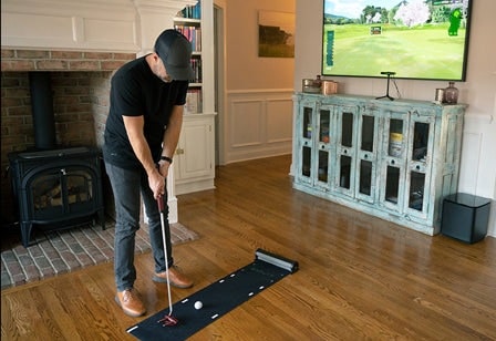 Man practicing indoor golf putting at home