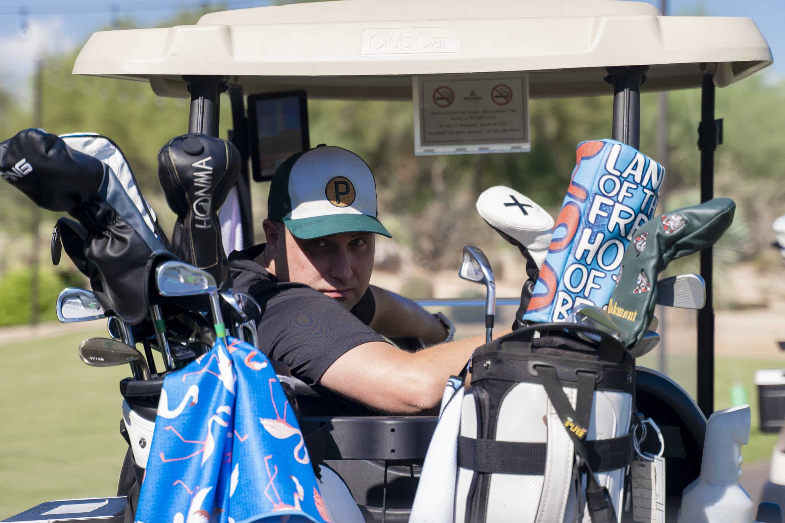 Golfer sitting in cart with golf clubs