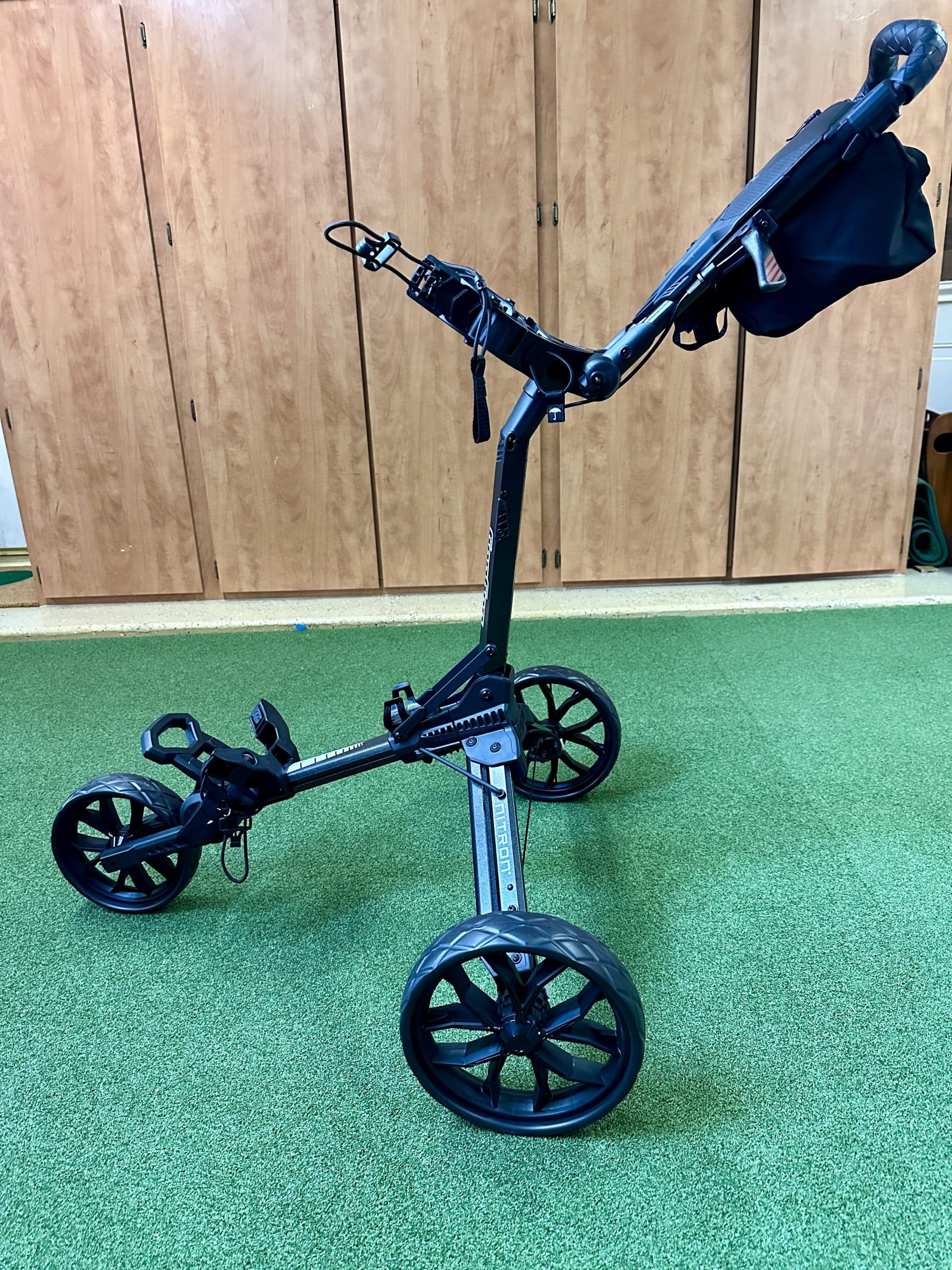 Three-wheel golf push cart on green floor